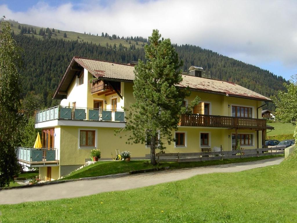 a large yellow house with a tree in front of it at Haus Alpenblick in Oberjoch