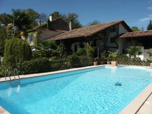 a large blue swimming pool in front of a house at Chambres d'Hôtes de Pesquès in Termes-dʼArmagnac
