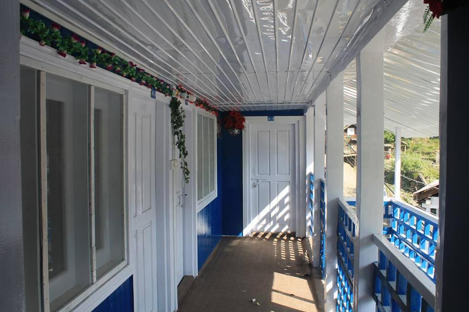 a front porch with a blue and white house at Sharda Highland Hotel in Shardi