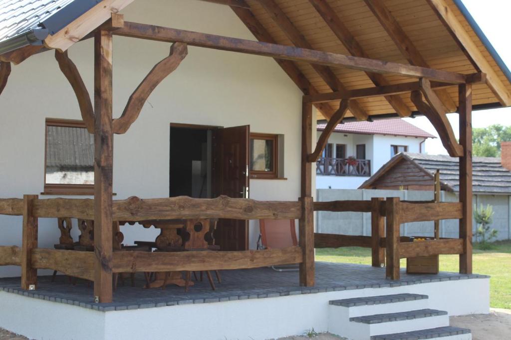 a house with a wooden pavilion on the porch at Domek letniskowy 8-osobowy nad jeziorem Wilczyńskim in Świętne