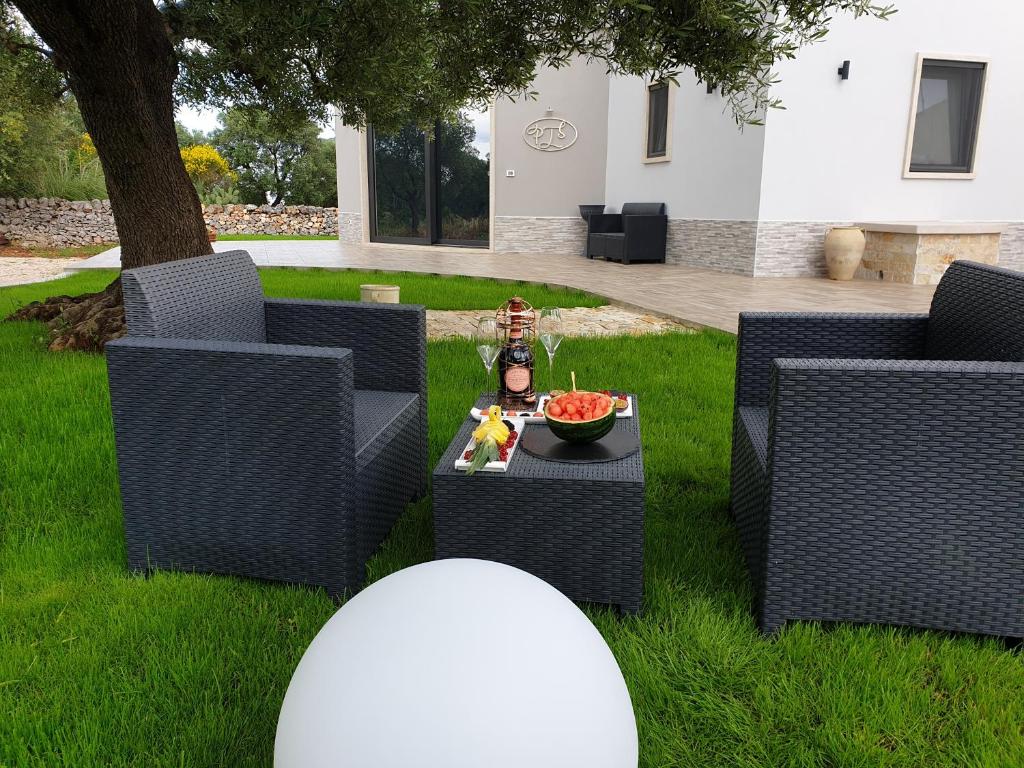 un patio con sillas y una mesa en el césped en Pandora Luxury Suite, en Carovigno