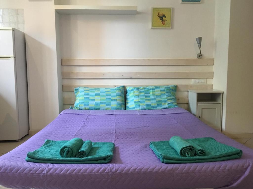 Una cama morada con dos toallas verdes. en Tra S.Orsola e Fiera, en Bolonia