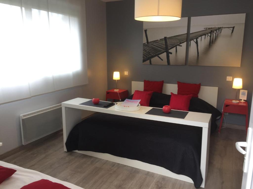 - une chambre avec un lit doté d'oreillers rouges et d'une table dans l'établissement AUX PETITS BAGANAIS, à Lacanau