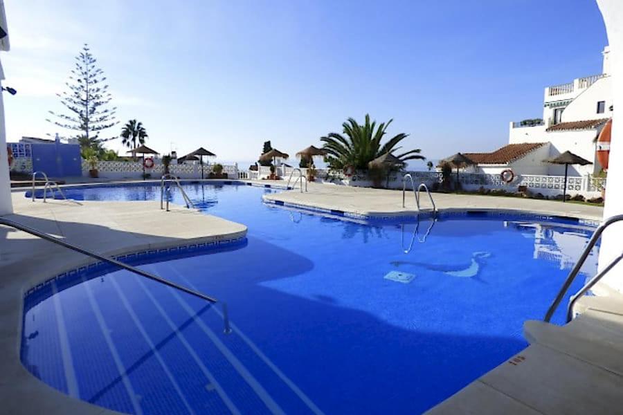 a large swimming pool with blue water at Hotel Bajamar Ancladero Playa in Nerja