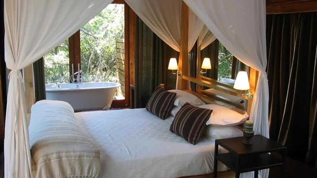 a bedroom with a bed and a bath tub and a tub at Hideaways Lazuli Bush Lodge, Hluhluwe in Hluhluwe