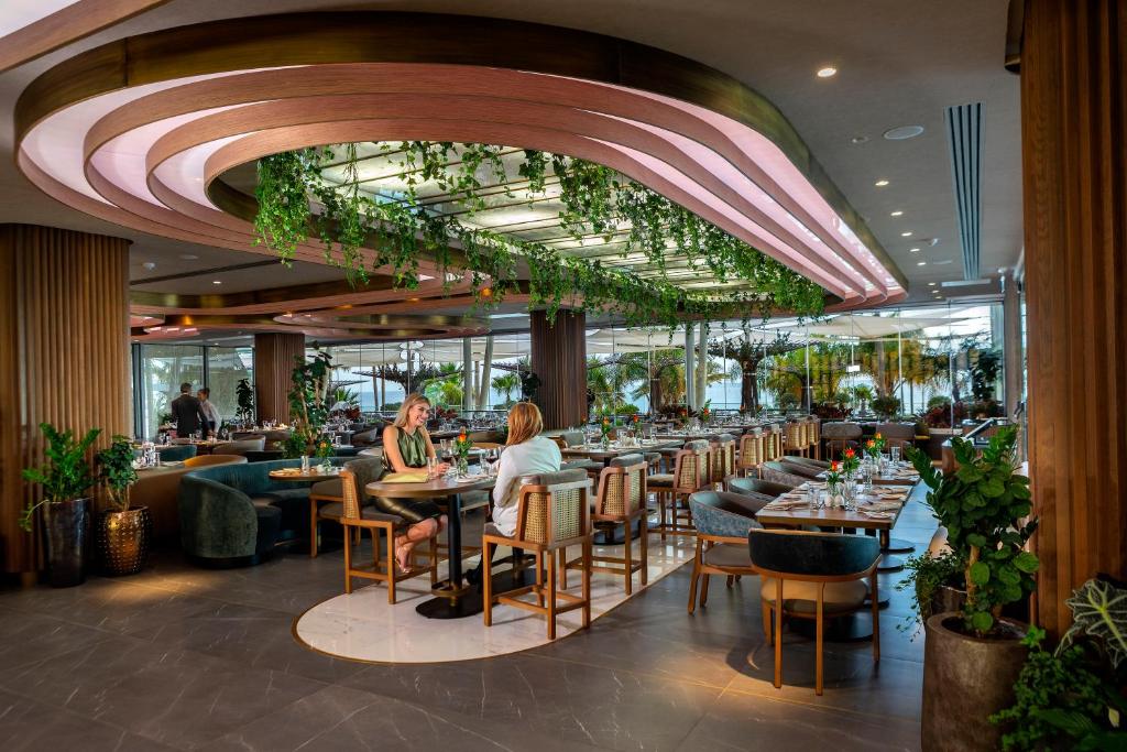 a restaurant with tables and people sitting at them at Amathus Beach Hotel Limassol in Limassol
