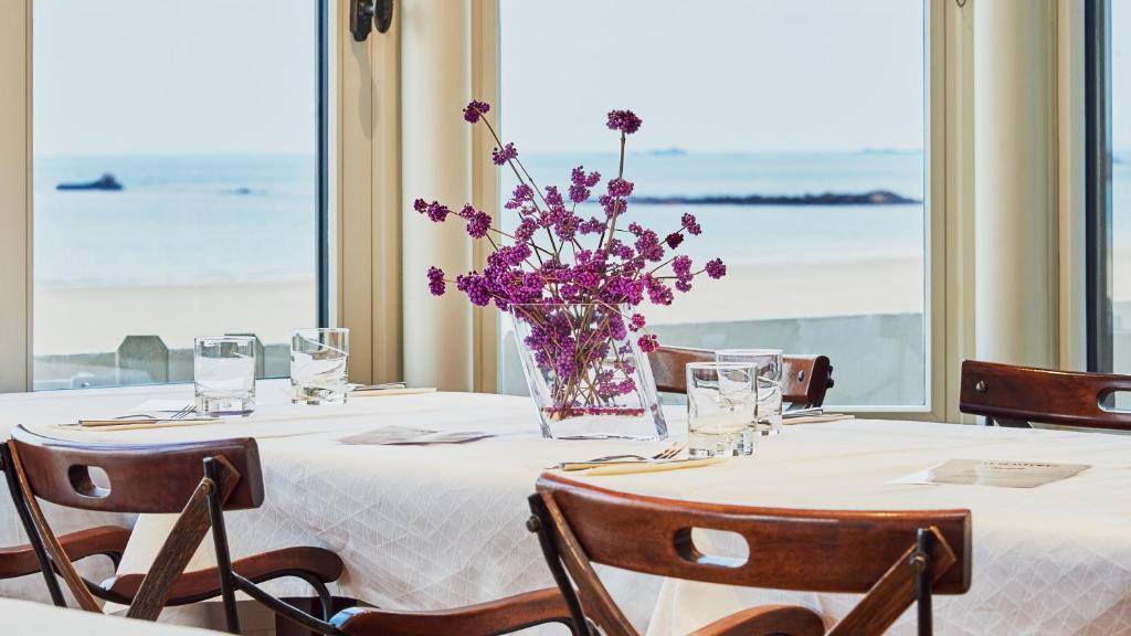 a table with a vase of purple flowers on it at Hôtel Le Beaufort in Saint Malo