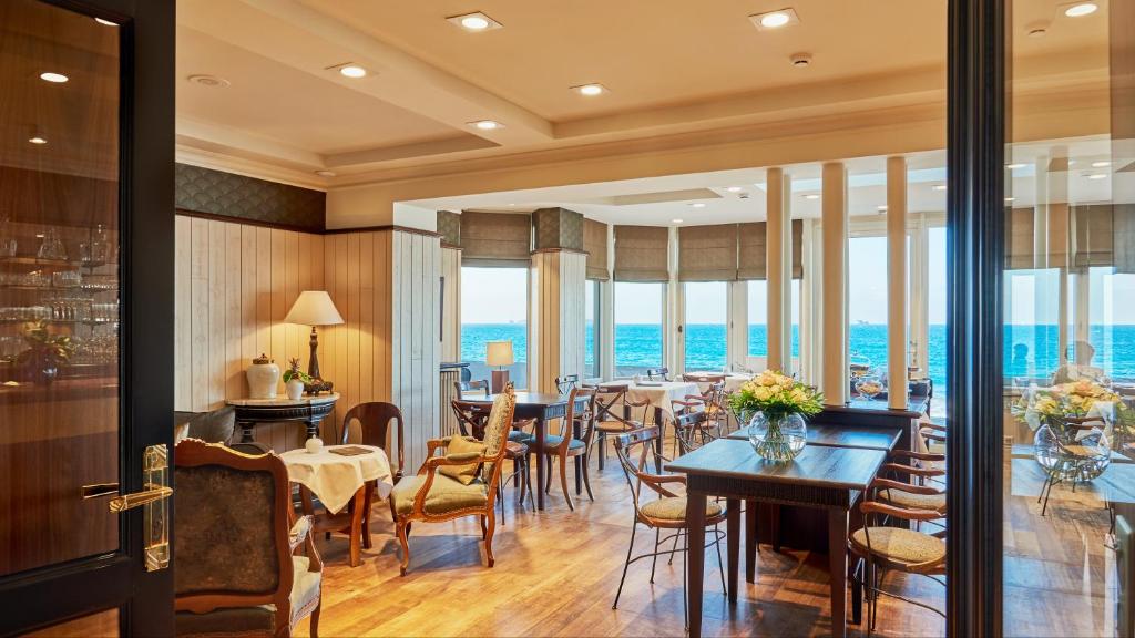 a restaurant with tables and chairs and a view of the ocean at Hôtel Le Beaufort in Saint Malo