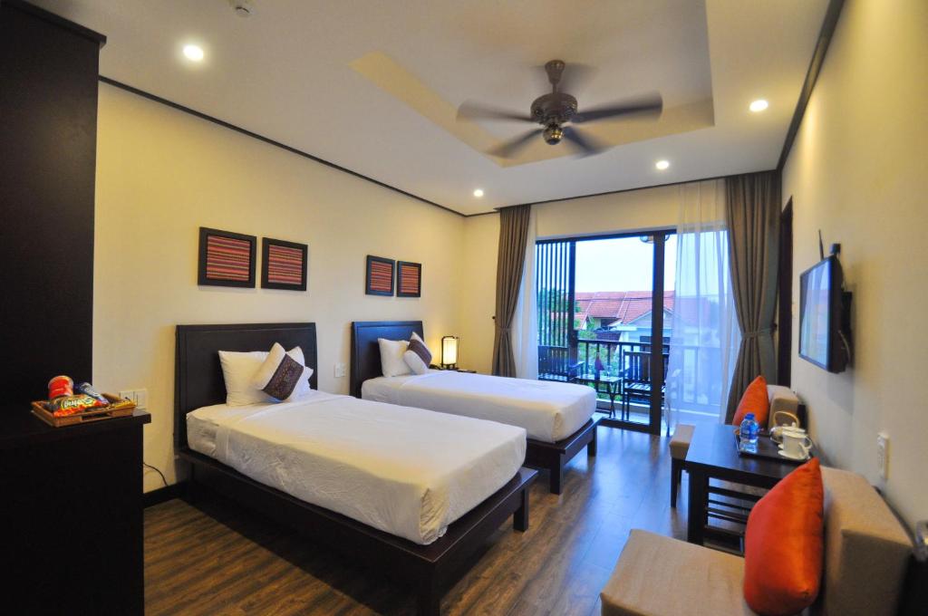 Habitación de hotel con 2 camas y ventilador de techo. en The Quin Riverside Villa en Hoi An