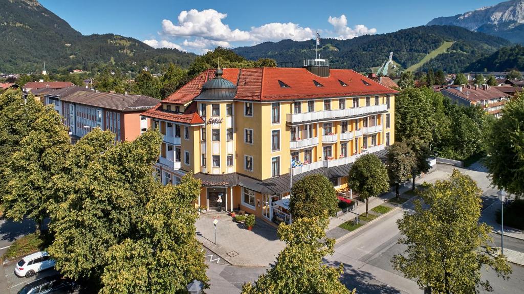 un grand bâtiment jaune avec un toit rouge dans l'établissement Hotel Vier Jahreszeiten, à Garmisch-Partenkirchen