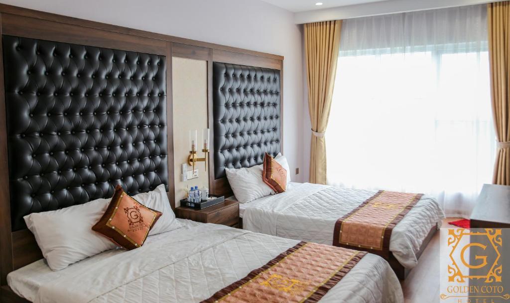 a bedroom with two beds and a large window at Golden Coto Hotel in Đảo Cô Tô