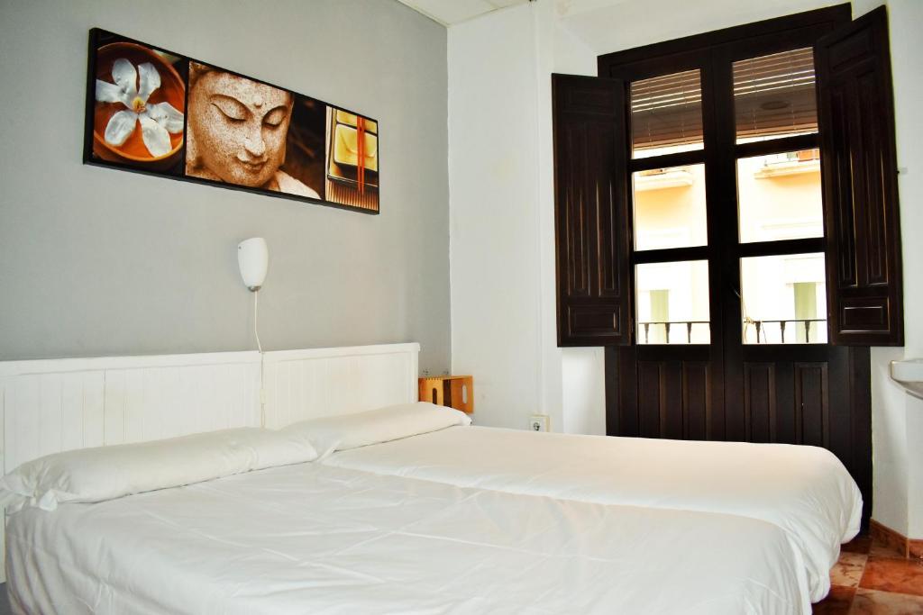 Un dormitorio con una cama blanca y una ventana. en Pension Castil, en Granada