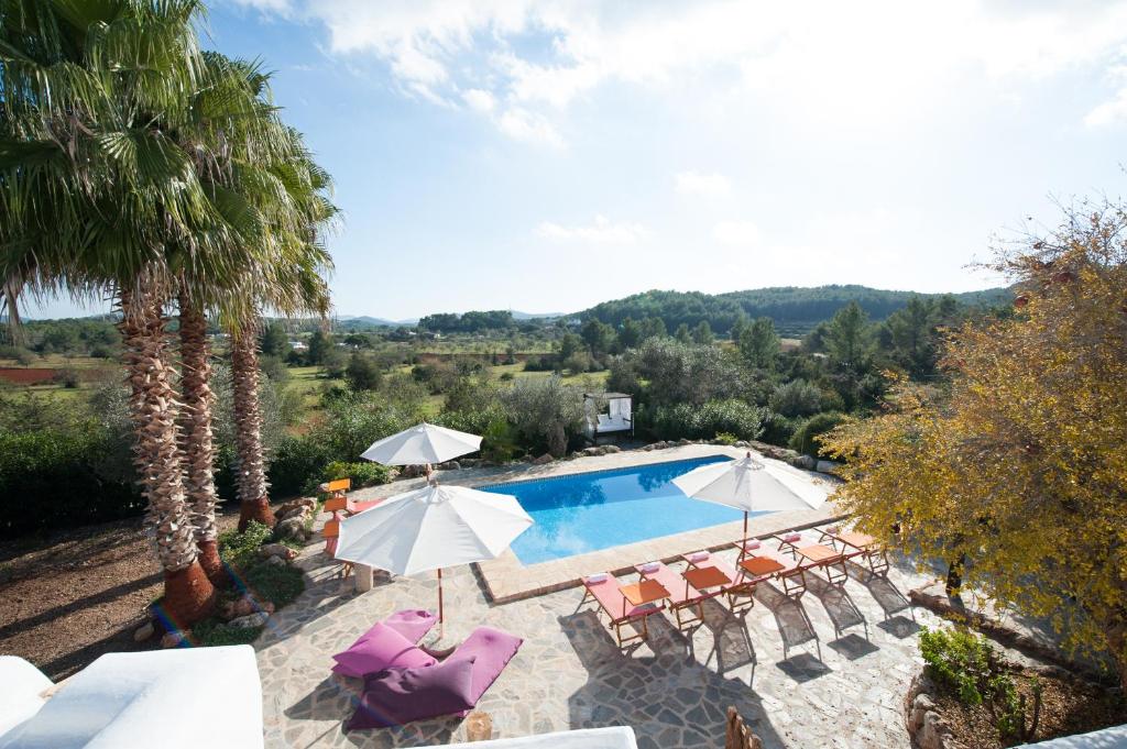 an outdoor swimming pool with chairs and umbrellas at Can Tierra Roja in Santa Gertrudis de Fruitera