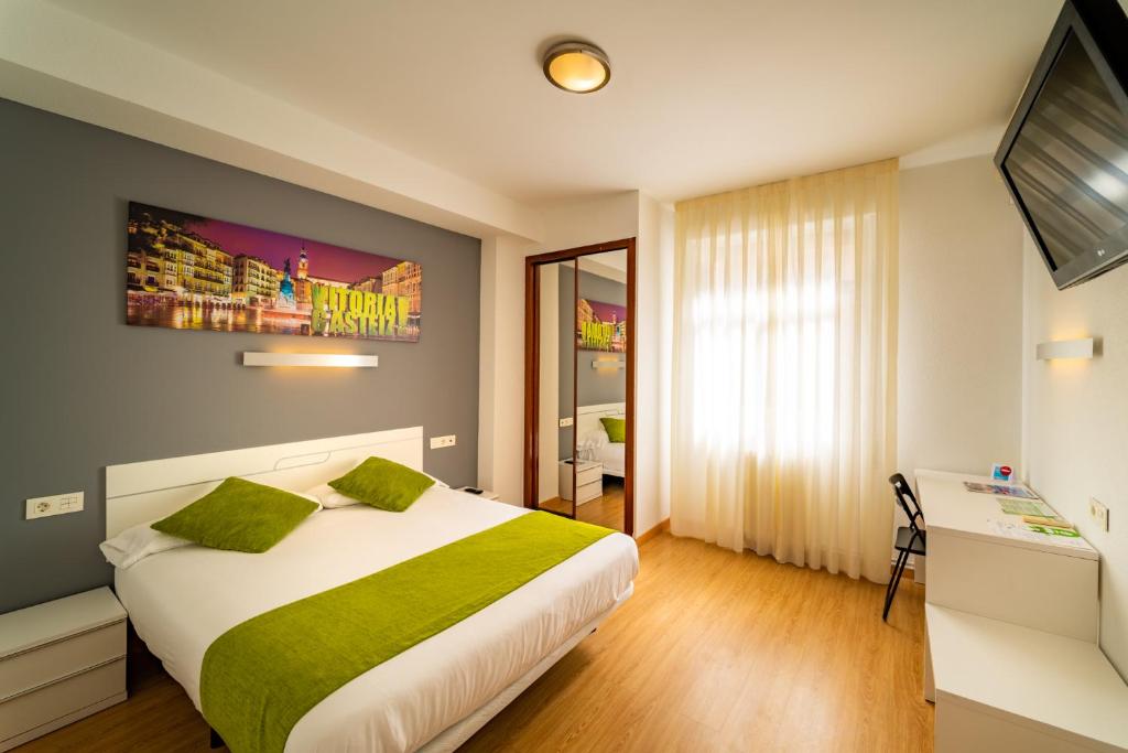 una camera d'albergo con letto e TV di Hotel Centro Vitoria AutoCheckIn a Vitoria-Gasteiz