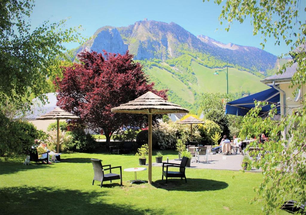 um jardim com cadeiras e um guarda-sol com montanhas ao fundo em Le Permayou em Accous