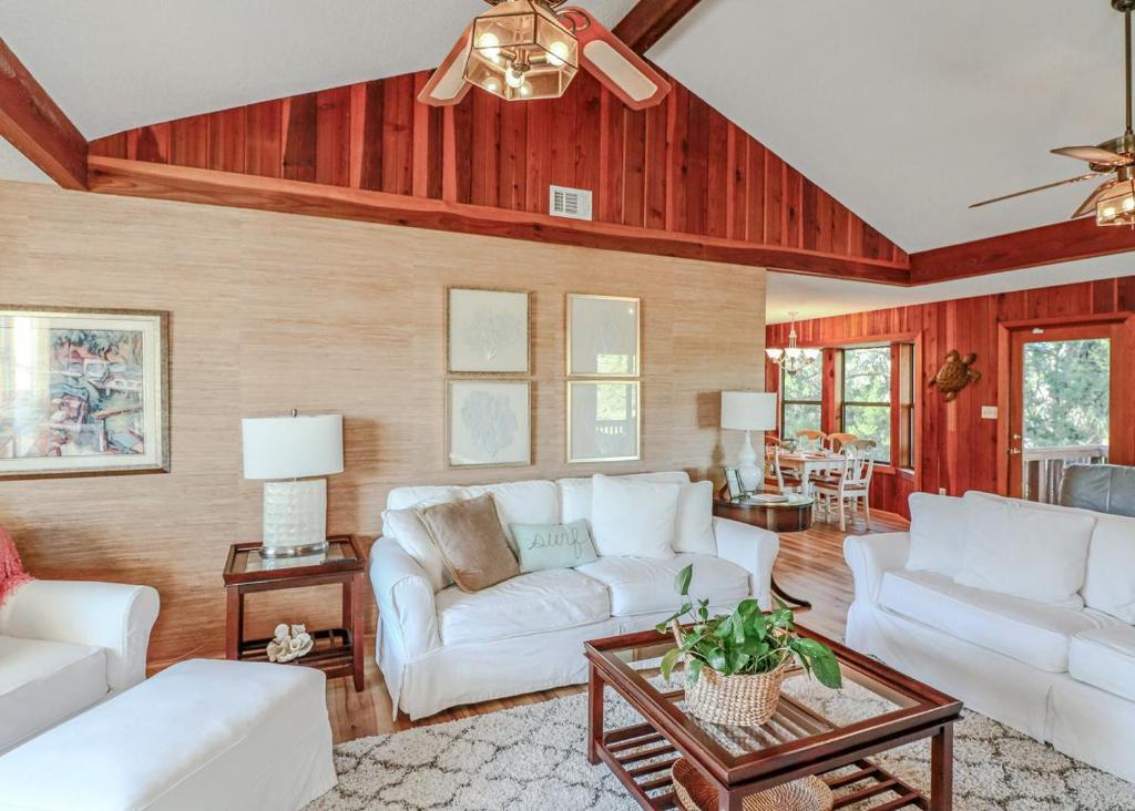 a living room with white furniture and wooden walls at Jack's Tybee Treehouse in Tybee Island