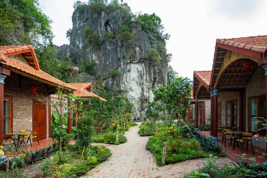 een pad tussen twee gebouwen met een berg op de achtergrond bij Ruby Homestay in Ninh Binh