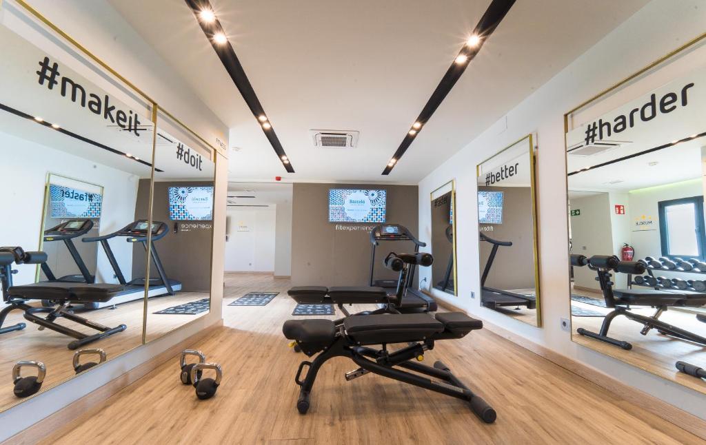 a gym with treadmills and ellipticals in a room with mirrors at Barceló Carmen Granada in Granada