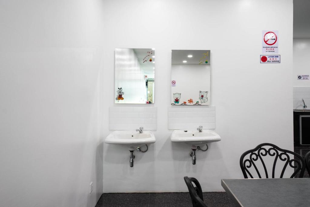 a bathroom with two sinks and two mirrors at Crystal Garden Hotel (Tasik Selatan) in Kuala Lumpur