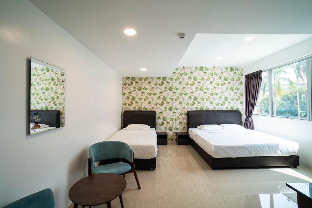 a bedroom with two beds and a chair and a table at Crystal Garden Hotel (Tasik Selatan) in Kuala Lumpur