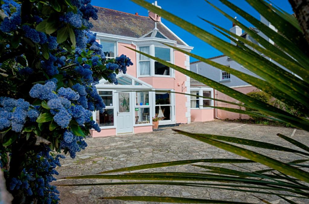 een roze huis met blauwe bloemen ervoor bij Potters Mooring Hotel in Teignmouth