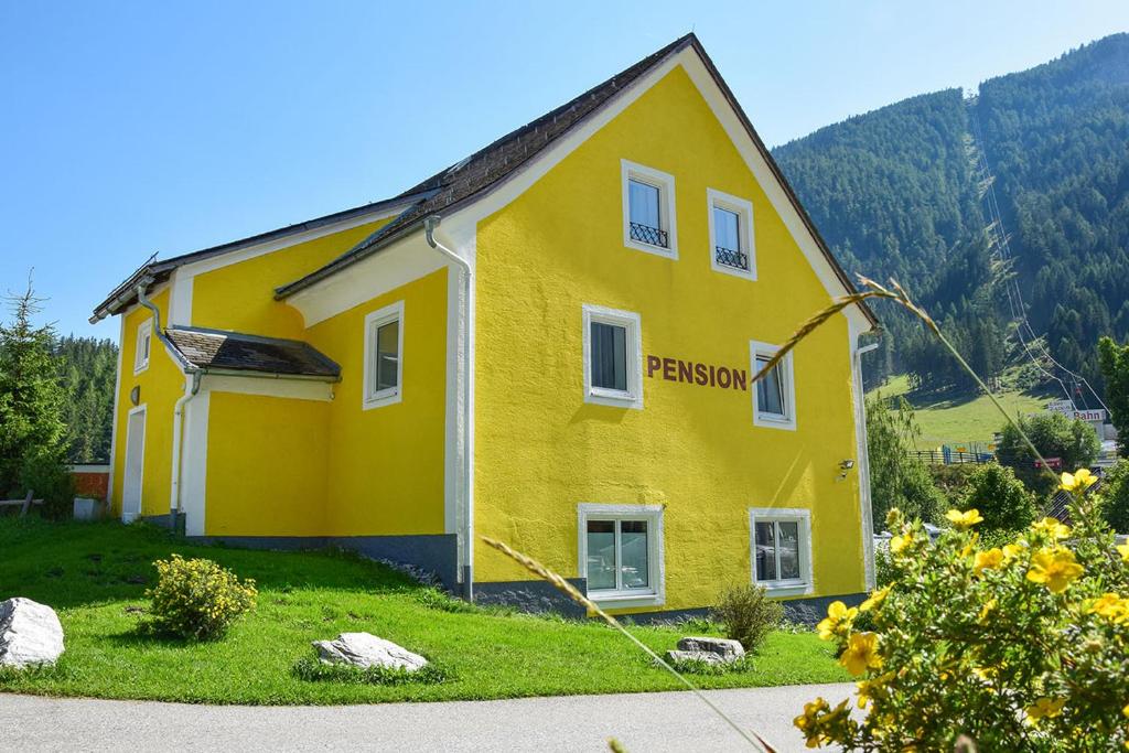 una casa amarilla con un cartel en el costado. en Pension Schizentrum Grosseck - Speiereck, en Mauterndorf