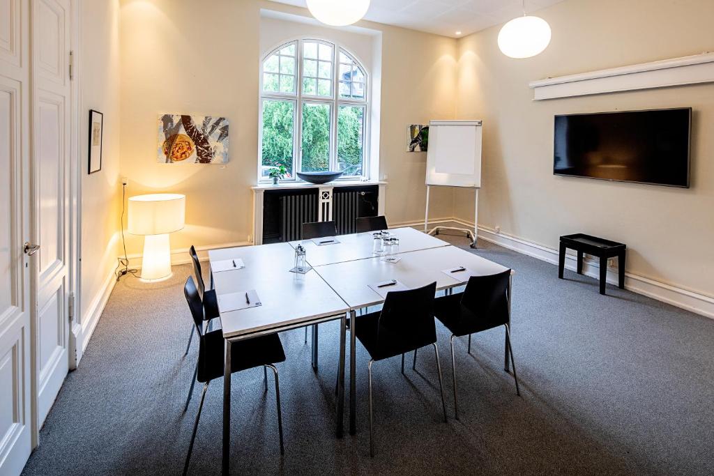 a meeting room with a white table and chairs at First Hotel Grand in Odense