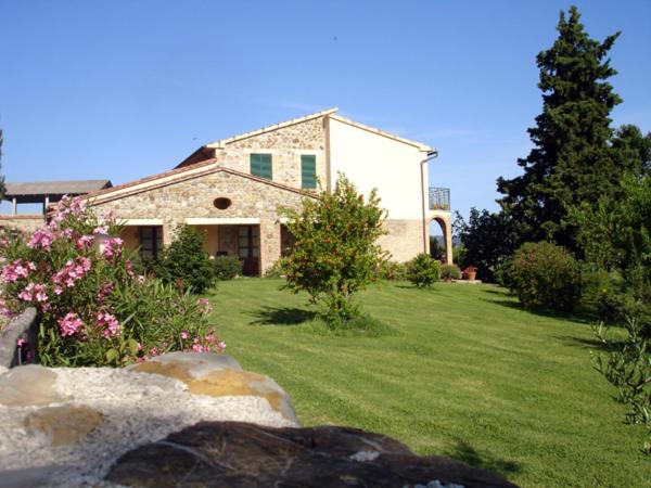 uma grande casa de pedra com um quintal com flores em Agriturismo Podere Micitto em Usi