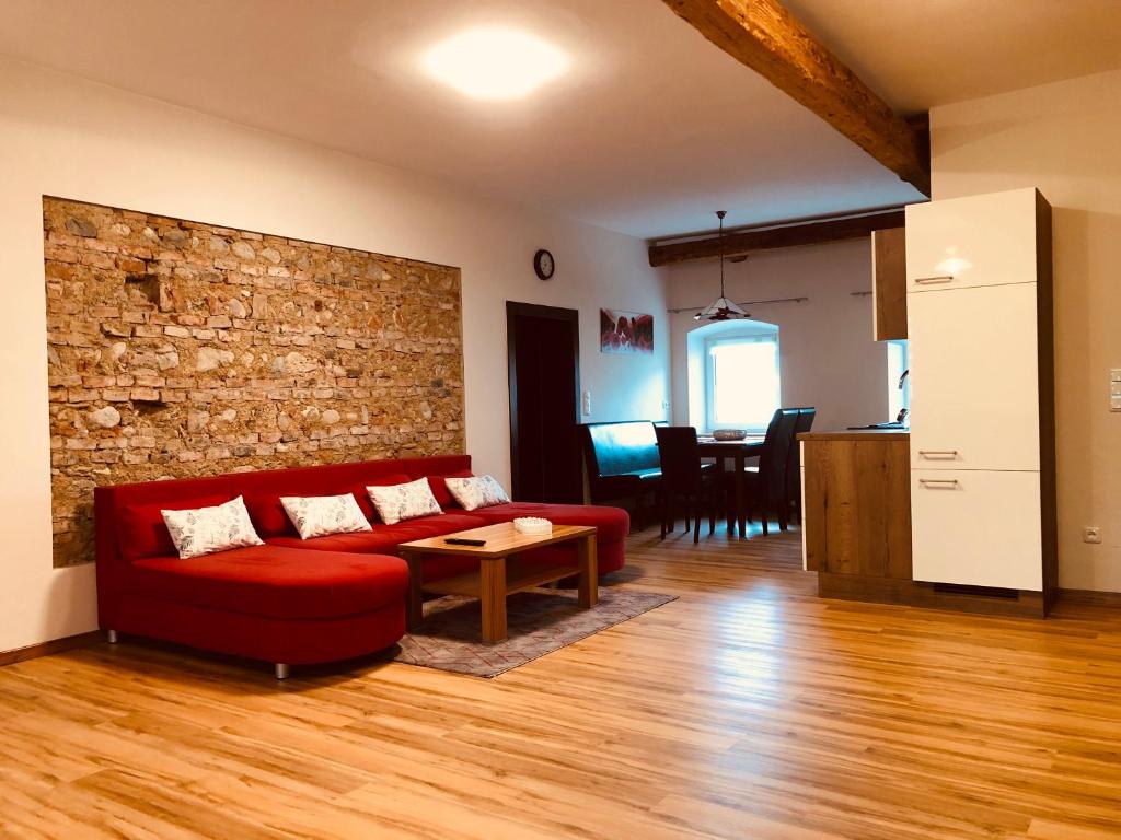 a living room with a red couch and a brick wall at Ferienwohnung Klampfermühle in Vorchdorf