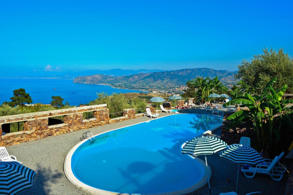 a swimming pool with umbrellas and a view of the ocean at Agriturismo Santa Margherita in Gioiosa Marea