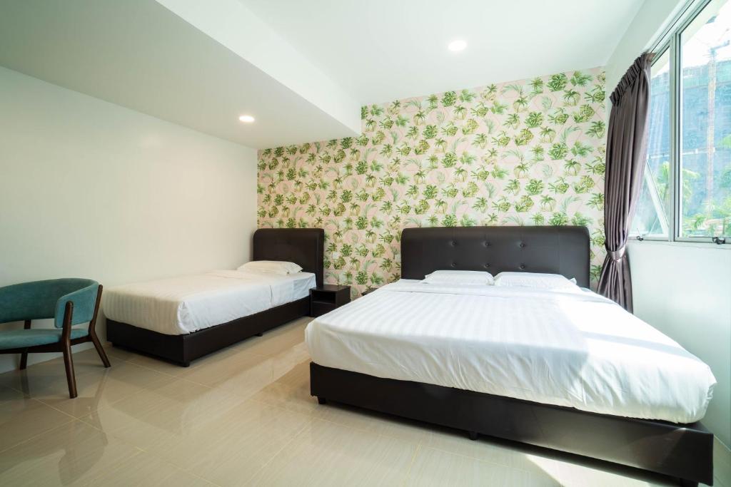 a bedroom with two beds and a chair and a window at Crystal Garden Hotel (Tasik Selatan) in Kuala Lumpur