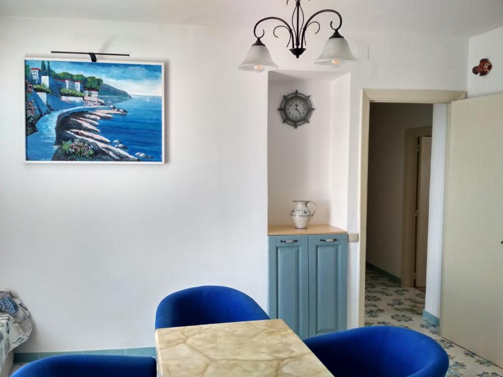 une salle à manger avec des chaises bleues et un tableau mural dans l'établissement La casa Azzurra, à Ischia