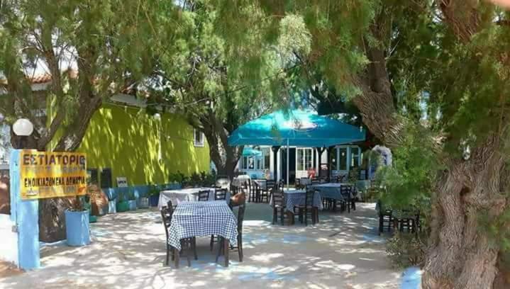 a group of tables and chairs under a blue umbrella at Pension Balos in Koumeika
