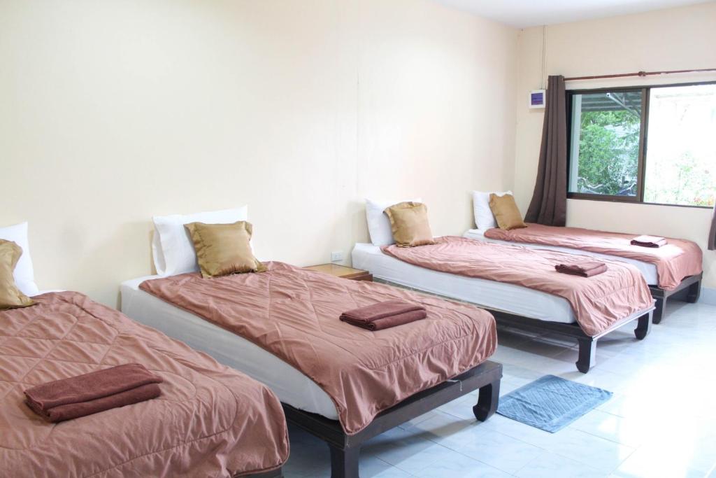 três camas num quarto com lençóis vermelhos em Sirikul Mansion em Nai Yang Beach