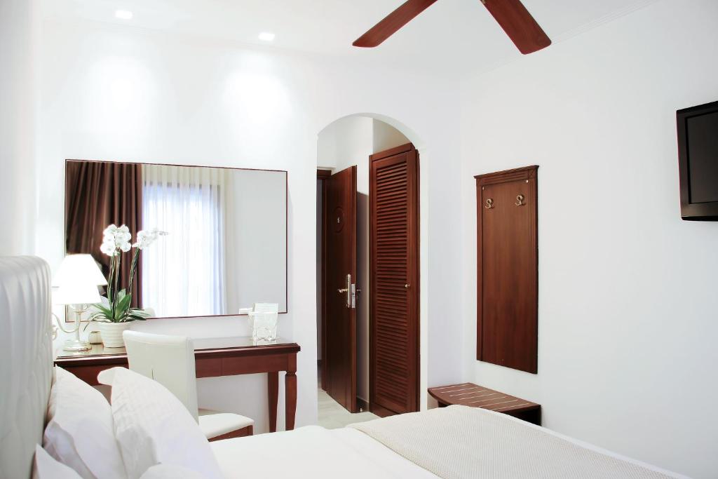 a bedroom with a bed and a desk and a mirror at Armata Boutique Hotel in Spetses