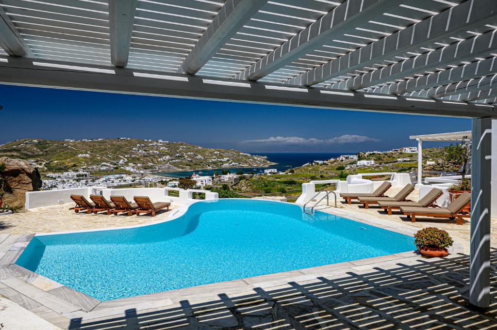 a swimming pool with lounge chairs and a view of the ocean at 9 Muses Villas Mykonos in Ornos