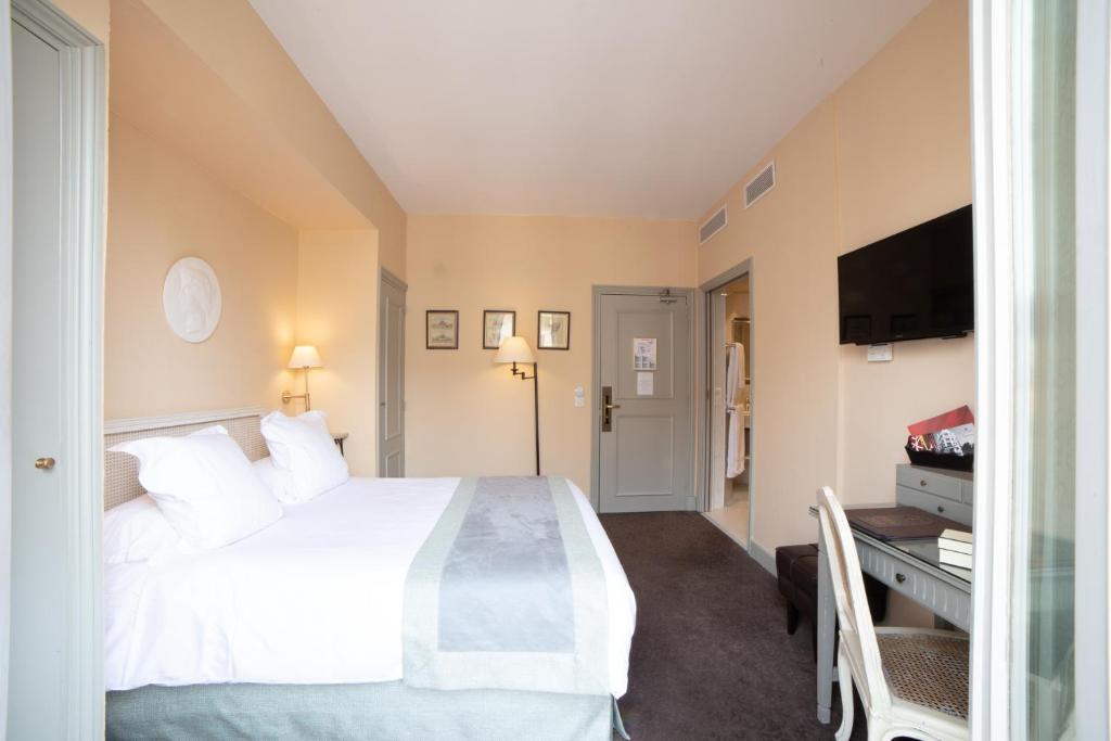 a bedroom with a white bed and a flat screen tv at Le Cavendish in Cannes