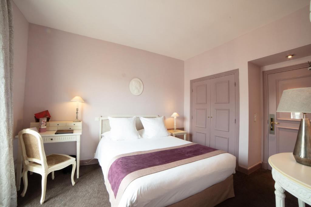 a hotel room with a large bed and a desk at Le Cavendish in Cannes
