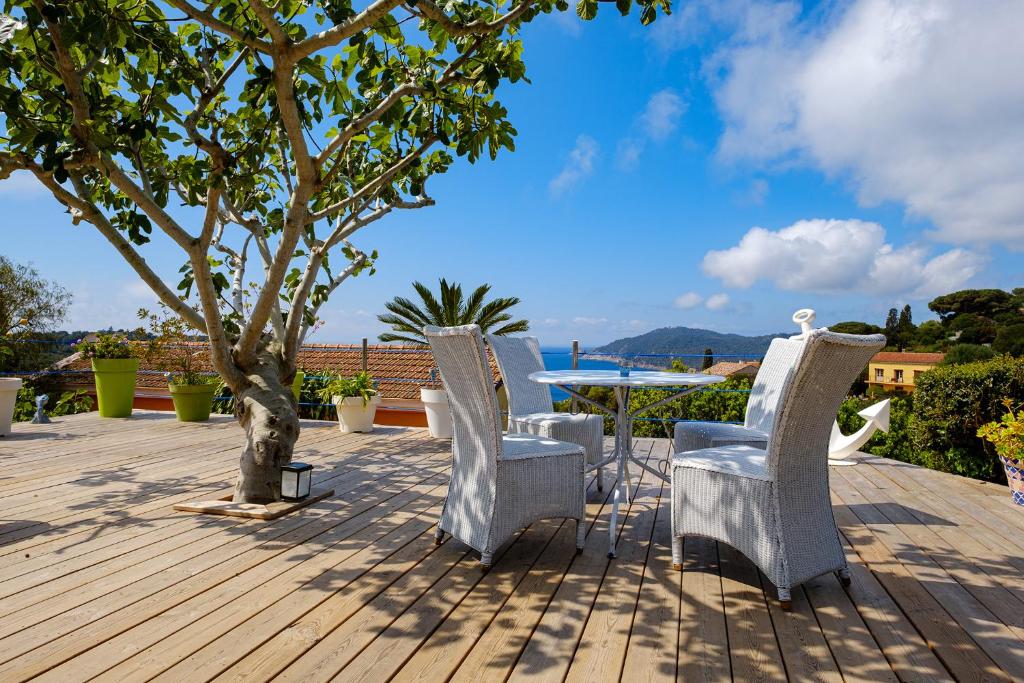 una terraza con sillas, una mesa y un árbol en Absolument Levant, en Isla de Levant