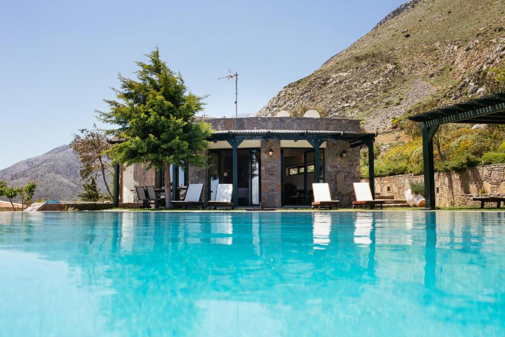 a pool with chairs and a house with a mountain at Aetovigla Guesthouse in Krousón