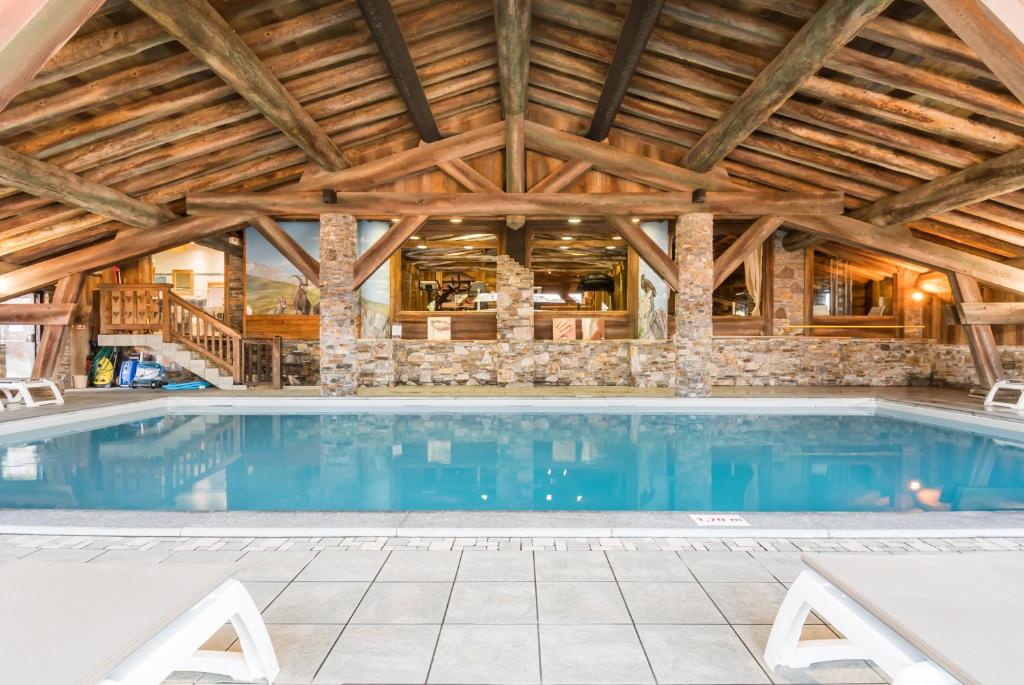 a large swimming pool in a building with a wooden ceiling at Résidence Pierre &amp; Vacances Premium Les Alpages de Chantel in Arc 1800
