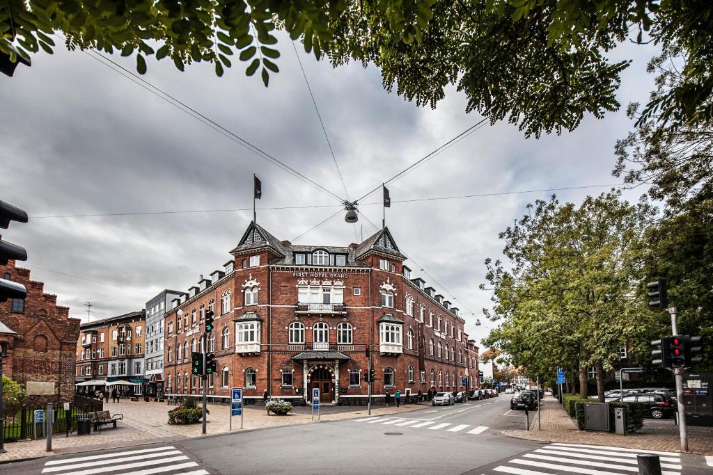 un grand bâtiment en briques rouges dans une rue de la ville dans l'établissement First Hotel Grand, à Odense