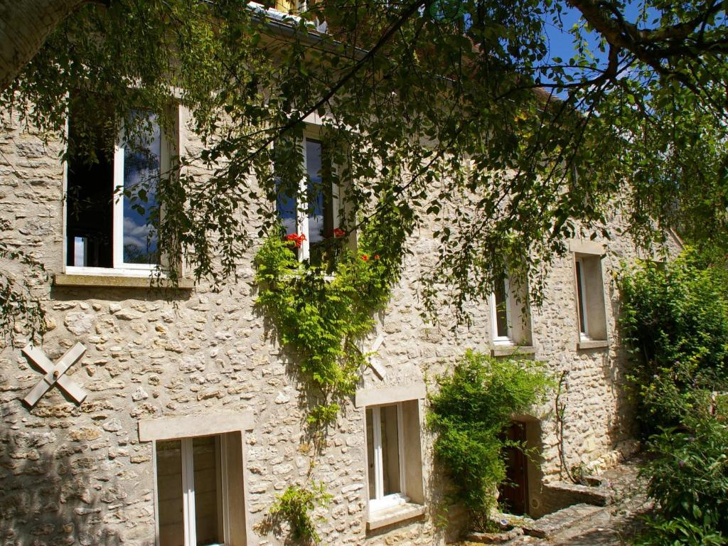 a stone building with windows and ivy on it at La Musardine en Vexin in Omerville