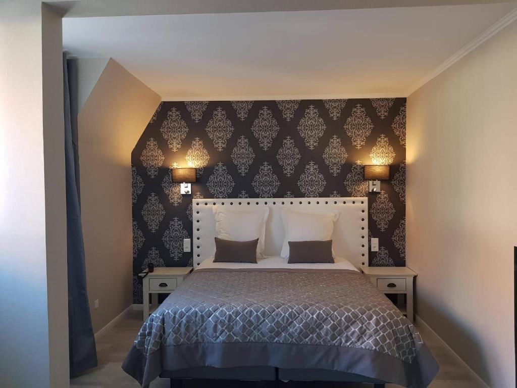 a bedroom with a large bed with a black wall at Le Trophée Boutique Hôtel Spa- La Loggia Appart'hôtel in Deauville