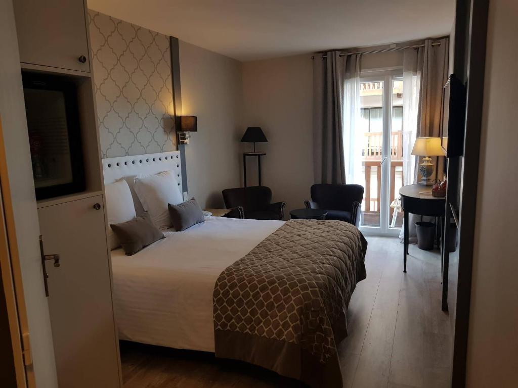 a hotel room with a large bed and a window at Le Trophée Boutique Hôtel Spa- La Loggia Appart'hôtel in Deauville