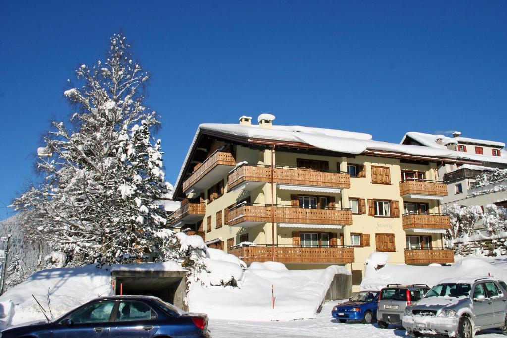クロスタースにあるMonami Apartments Klosters, Apt. Solavers No 1の雪に車を停めた大きな建物