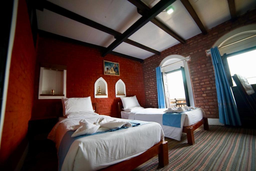 a bedroom with two beds and a brick wall at Bandipur chhen in Bandīpur
