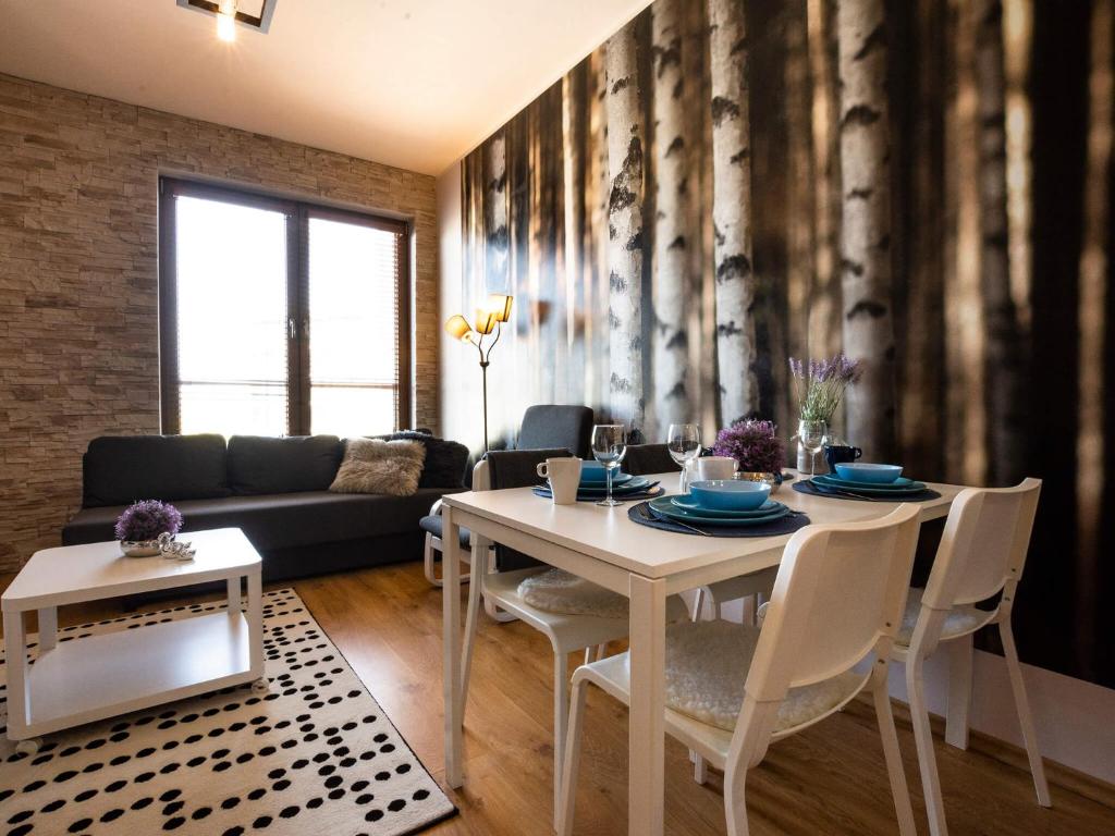 een woonkamer met een witte tafel en stoelen bij VacationClub - Olympic Park Apartament B404 in Kołobrzeg
