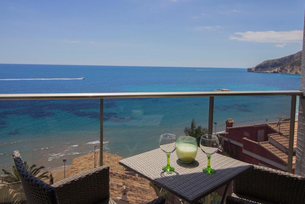 dos copas de vino sentadas en una mesa en un balcón en Beautiful frontline apartment MELIORIA with panoramic seaview, en Calpe