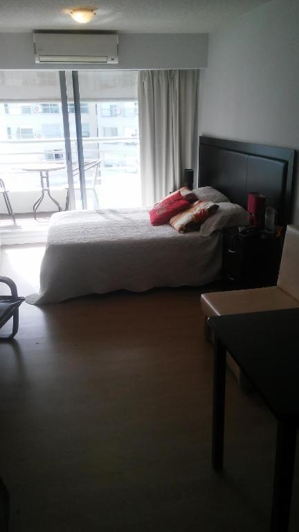 a bedroom with a bed and a large window at Edificio Go Pocitos in Montevideo